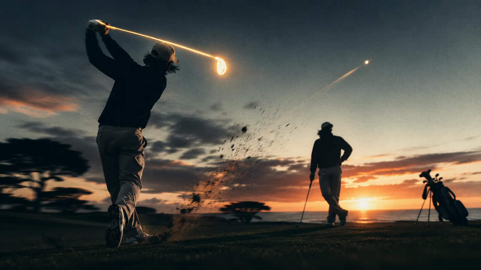 A golfer's follow-through at sunset, ball tracing into the sky while a playing partner watches